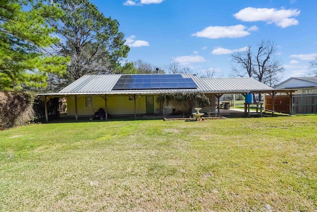 rear view of house with a carport, metal roof, a lawn, and solar panels