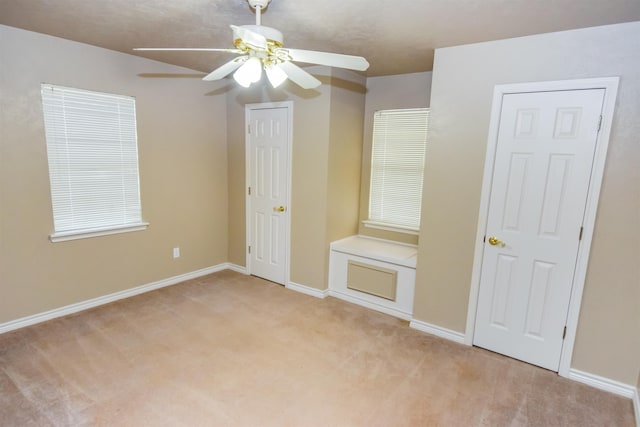 unfurnished bedroom featuring baseboards, a ceiling fan, and light colored carpet