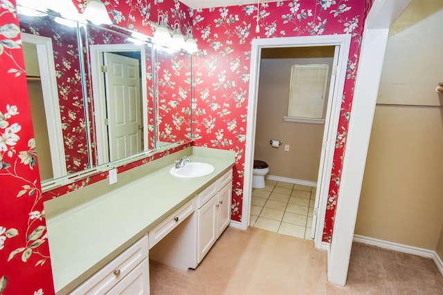 bathroom with baseboards, vanity, toilet, and wallpapered walls