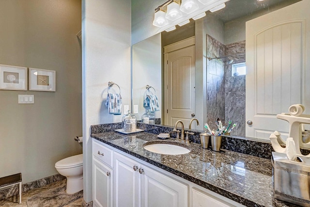 bathroom featuring a tile shower, vanity, and toilet