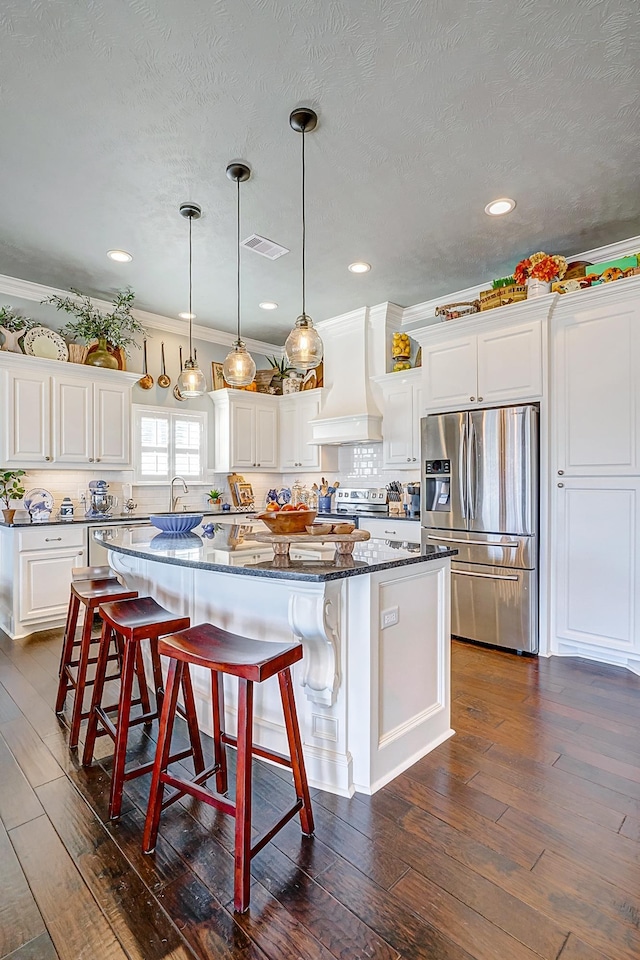 kitchen featuring premium range hood, backsplash, a kitchen island, and stainless steel appliances