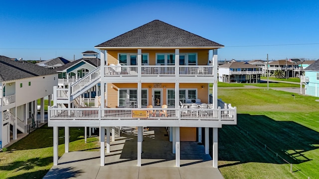 rear view of property featuring a lawn, a balcony, and a carport