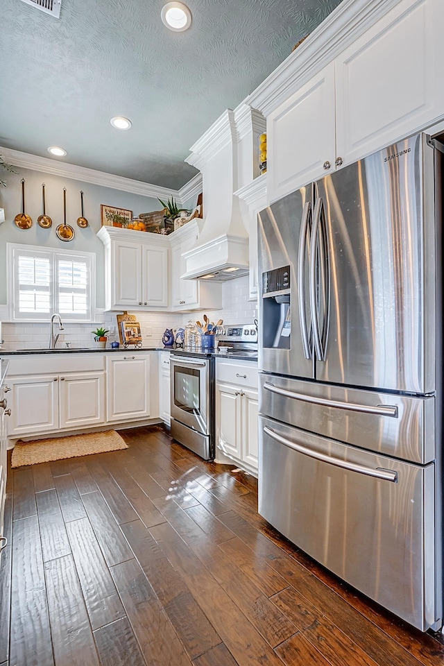 kitchen with appliances with stainless steel finishes, backsplash, premium range hood, and white cabinetry