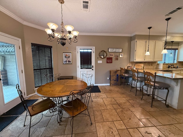 dining room featuring sink, a chandelier, a textured ceiling, and ornamental molding