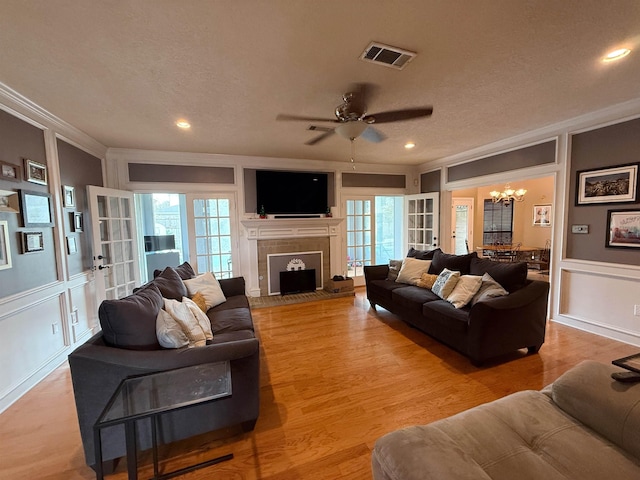 living room featuring crown molding, light hardwood / wood-style floors, and ceiling fan with notable chandelier