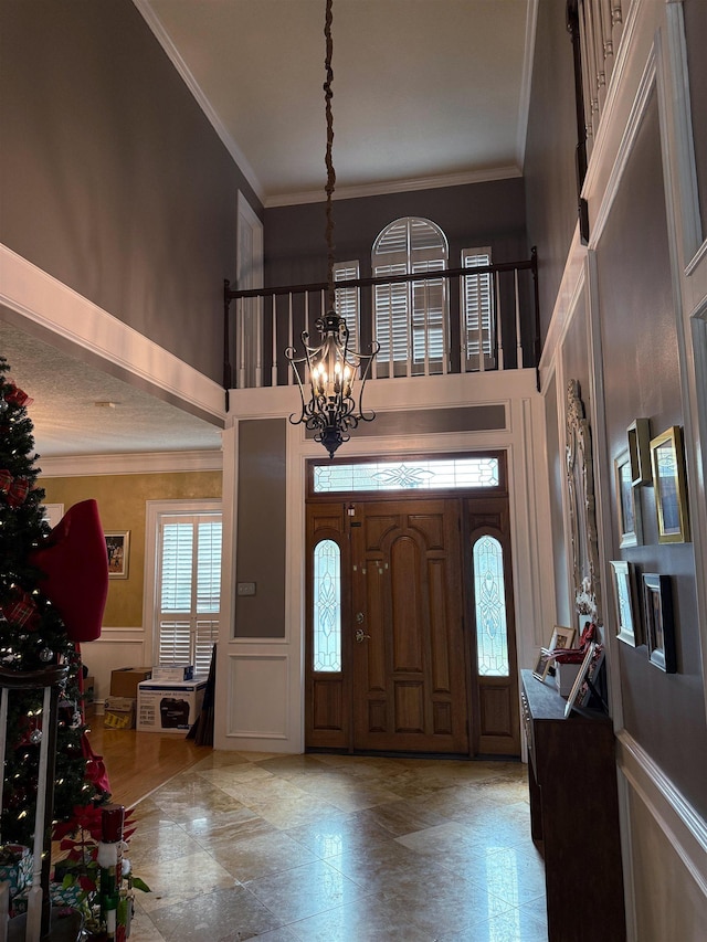 entrance foyer featuring crown molding, a chandelier, and a high ceiling