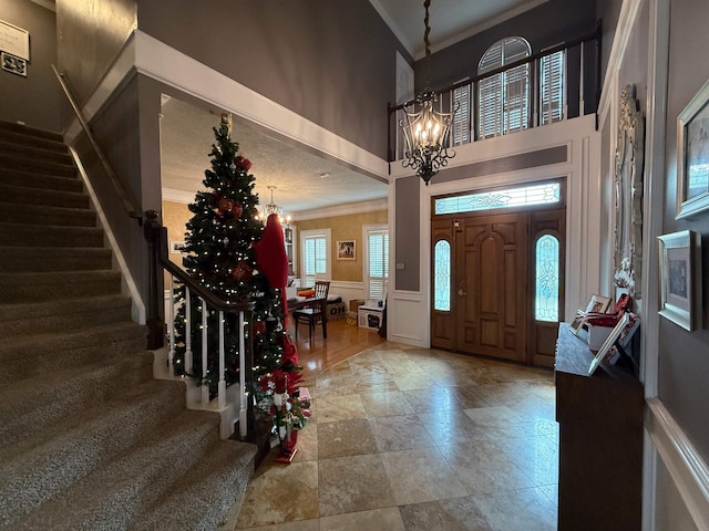 entrance foyer featuring crown molding, a towering ceiling, and an inviting chandelier