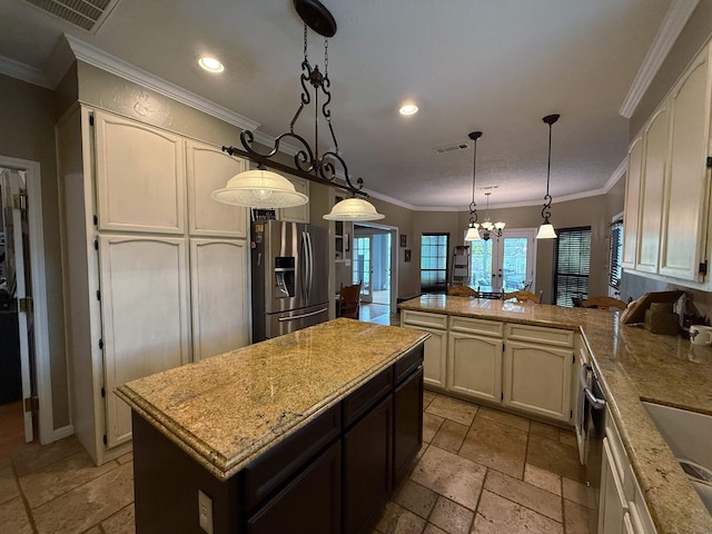 kitchen featuring a center island, hanging light fixtures, stainless steel fridge, light stone countertops, and a notable chandelier