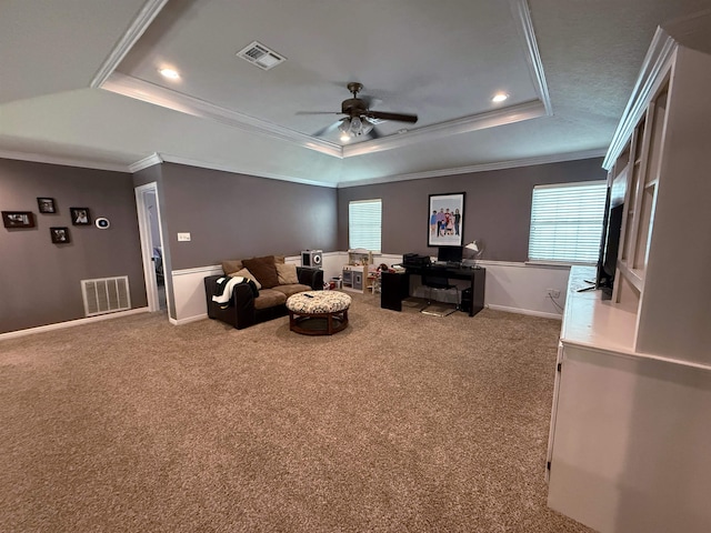 carpeted living room with ceiling fan, ornamental molding, and a tray ceiling