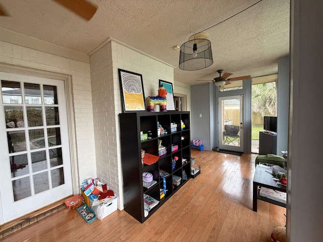 interior space featuring hardwood / wood-style floors, a textured ceiling, and brick wall