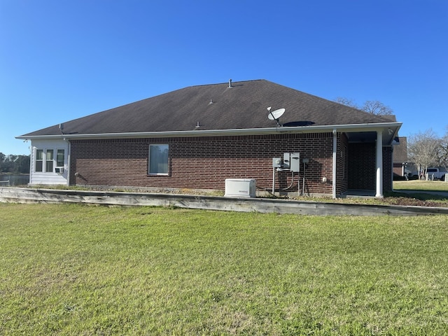 back of house with brick siding and a lawn