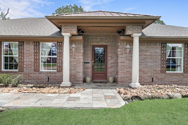 3590 Wheat Dr, Beaumont, TX 77706 - view of exterior entry with brick siding, a standing seam roof, and roof with shingles