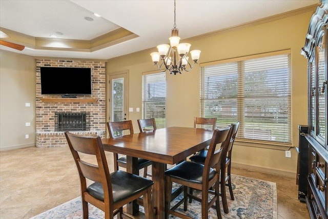 dining room featuring a fireplace, ornamental molding, a raised ceiling, and a chandelier