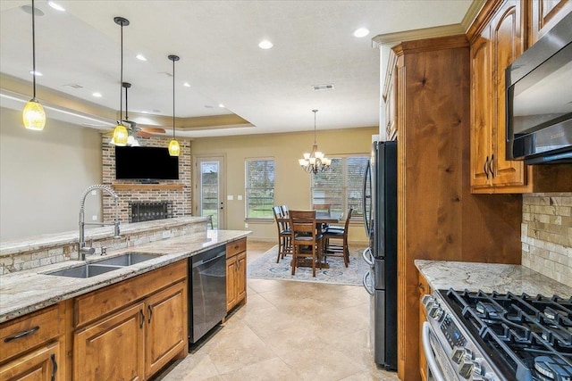 kitchen featuring light stone counters, a raised ceiling, sink, and black appliances