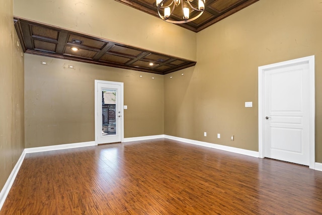 empty room featuring beam ceiling, dark hardwood / wood-style flooring, crown molding, and coffered ceiling