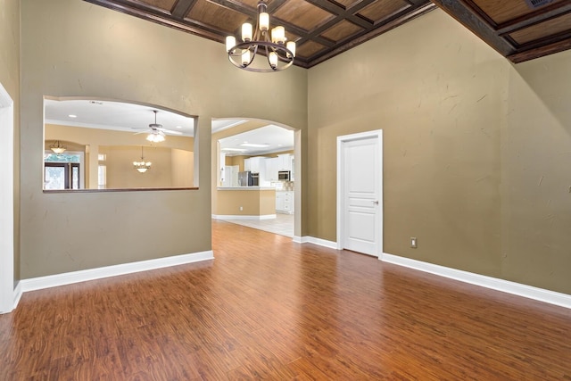 unfurnished living room featuring coffered ceiling, beamed ceiling, crown molding, hardwood / wood-style floors, and ceiling fan with notable chandelier