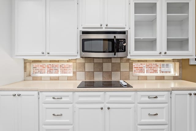 kitchen featuring black electric stovetop, white cabinetry, and backsplash