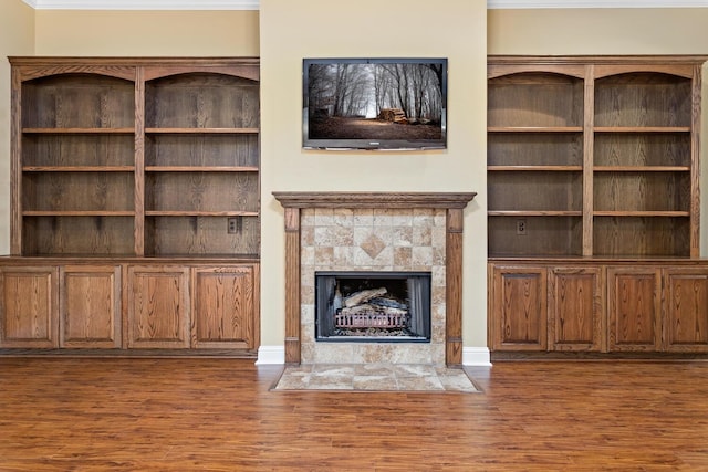 unfurnished living room featuring dark wood-type flooring and a tiled fireplace