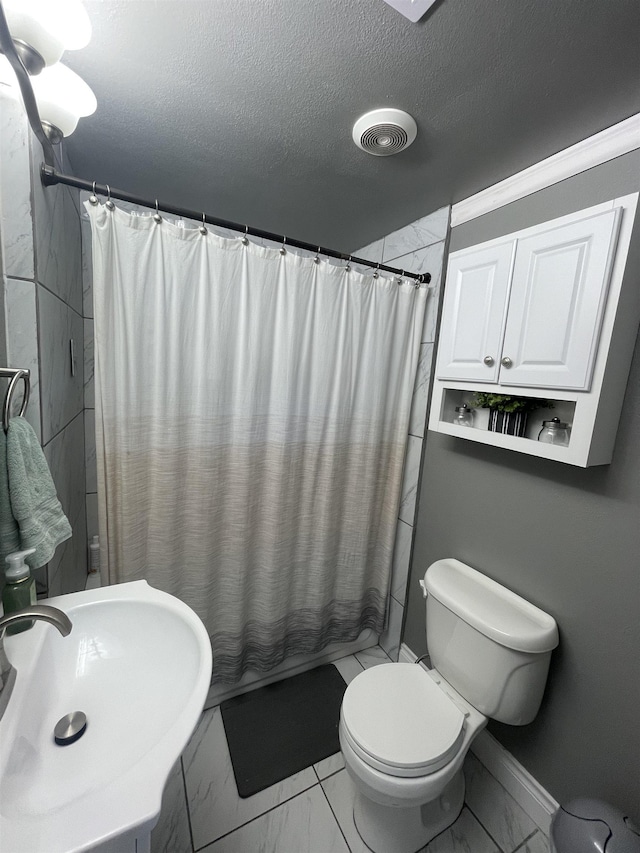 full bathroom featuring visible vents, a shower with curtain, marble finish floor, a textured ceiling, and a sink