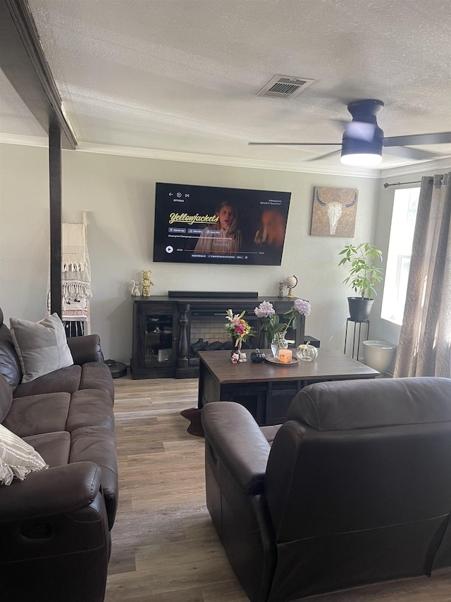 living area with a ceiling fan, visible vents, a textured ceiling, and wood finished floors