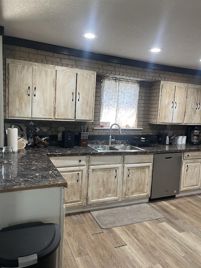 kitchen featuring a sink, light wood-style floors, stainless steel dishwasher, and light brown cabinetry