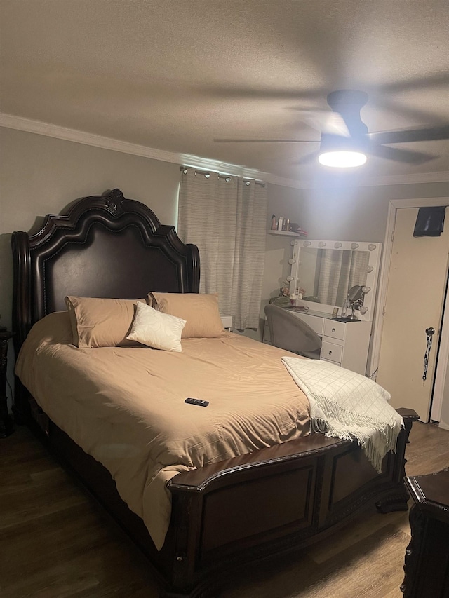 bedroom with a textured ceiling, ceiling fan, crown molding, and wood finished floors