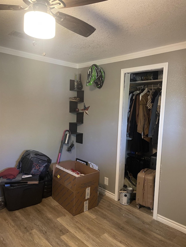 bedroom with ornamental molding, a closet, a textured ceiling, and wood finished floors