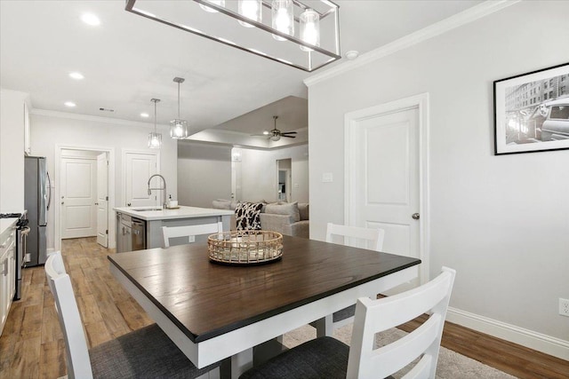 dining area featuring light hardwood / wood-style flooring, ceiling fan, ornamental molding, and sink