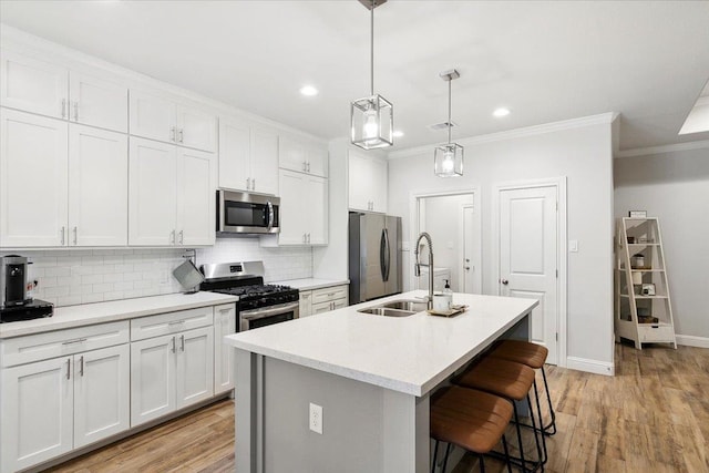 kitchen featuring a kitchen island with sink, white cabinets, and appliances with stainless steel finishes