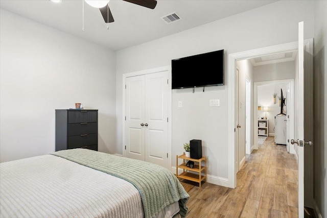 bedroom featuring ceiling fan, a closet, light hardwood / wood-style floors, and washer / dryer