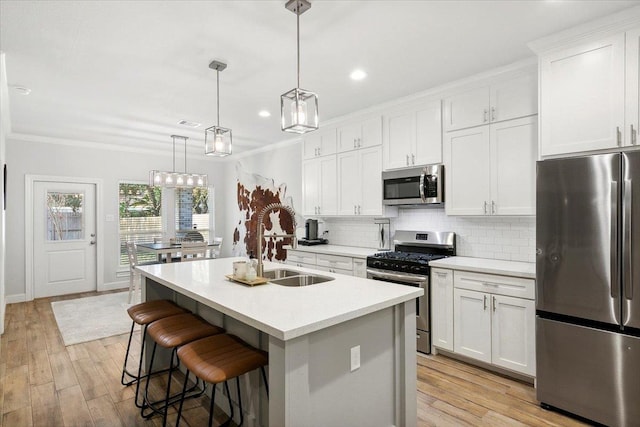 kitchen with a center island with sink, decorative light fixtures, white cabinets, and stainless steel appliances