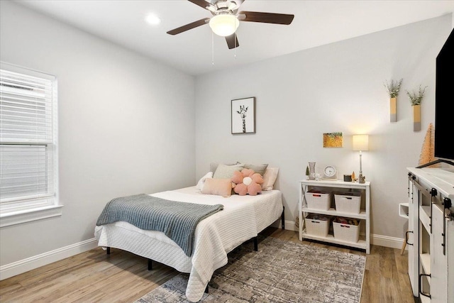 bedroom featuring hardwood / wood-style floors, ceiling fan, and multiple windows