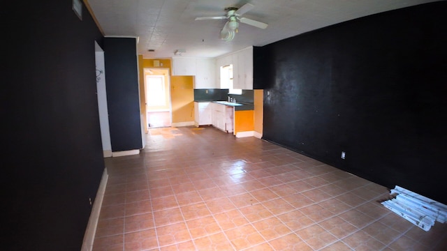 unfurnished living room with ceiling fan, light tile patterned flooring, and baseboards