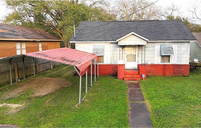 view of front of home with roof with shingles, a front yard, and brick siding