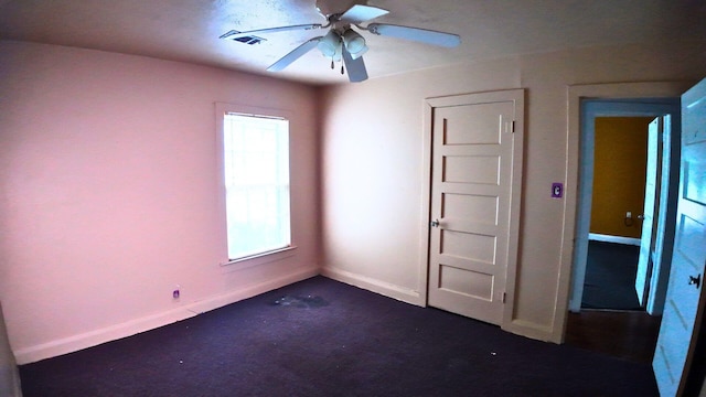 unfurnished bedroom with a ceiling fan, dark carpet, visible vents, and baseboards