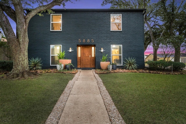 view of front facade featuring a lawn and brick siding