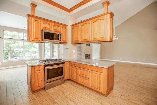 kitchen featuring kitchen peninsula, ceiling fan, stainless steel appliances, and light stone counters