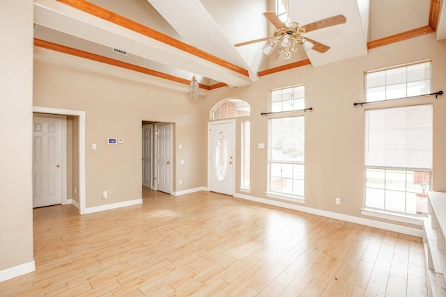 empty room featuring a high ceiling, light hardwood / wood-style floors, and ceiling fan