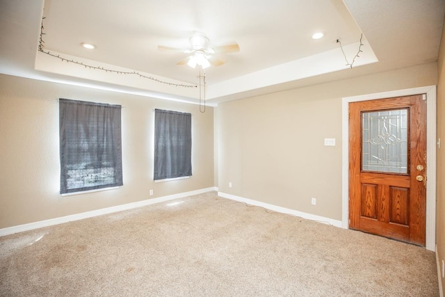 spare room with carpet flooring, ceiling fan, and a raised ceiling