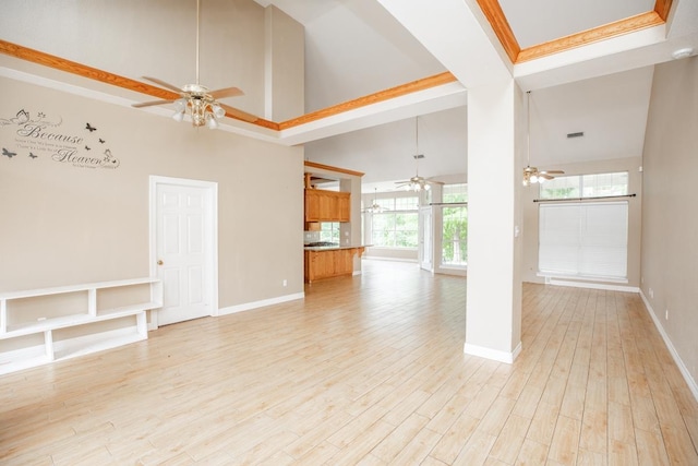 unfurnished living room with light wood-type flooring, a towering ceiling, and crown molding