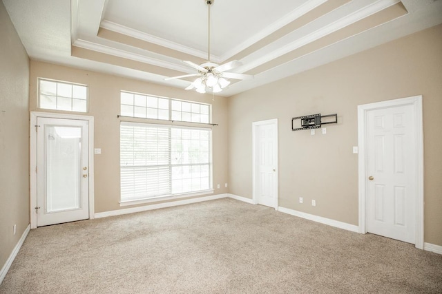 carpeted spare room with a raised ceiling, ceiling fan, and ornamental molding