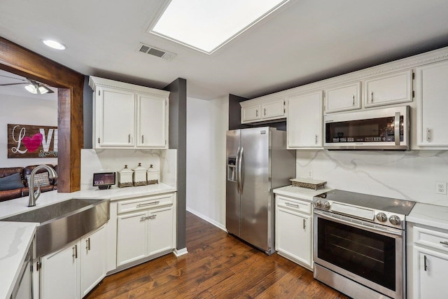 kitchen with white cabinets, dark wood-style floors, a sink, visible vents, and appliances with stainless steel finishes