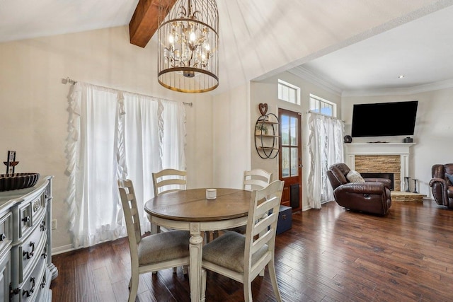 dining room with dark wood finished floors, ornamental molding, baseboards, a fireplace, and a notable chandelier