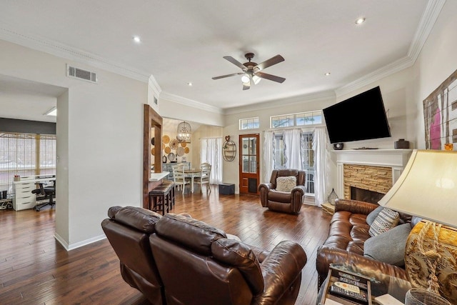 living area with visible vents, a ceiling fan, crown molding, hardwood / wood-style floors, and a fireplace