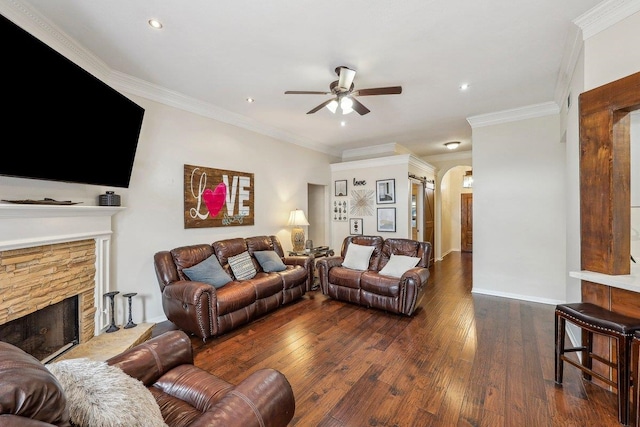 living room with arched walkways, ceiling fan, crown molding, hardwood / wood-style flooring, and a fireplace