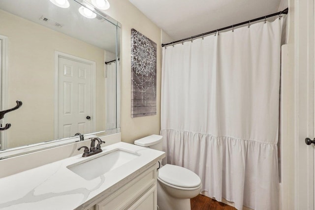 full bath featuring toilet, vanity, wood finished floors, and visible vents