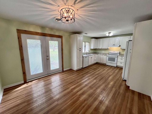 kitchen with dark wood-type flooring, under cabinet range hood, french doors, white appliances, and white cabinetry
