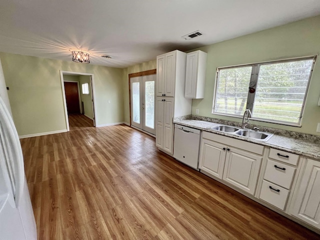 kitchen with dishwasher, white cabinetry, light wood-type flooring, and a sink