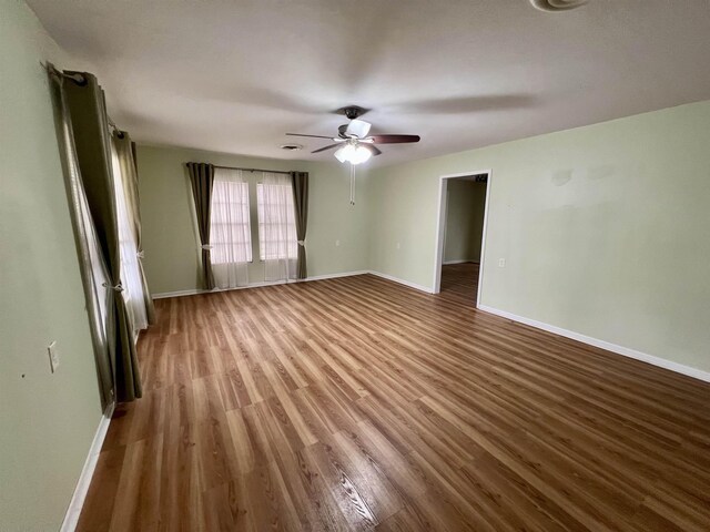 spare room featuring baseboards, wood finished floors, and a ceiling fan