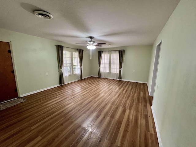 empty room with a ceiling fan, wood finished floors, and baseboards